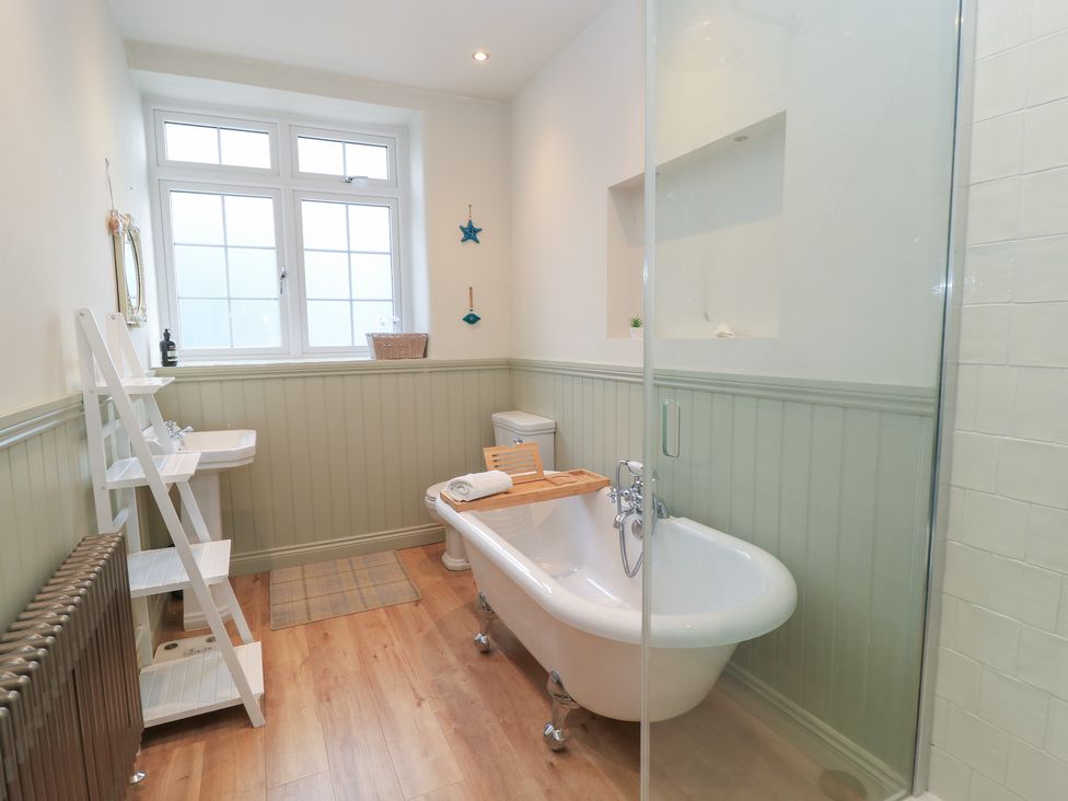 A bathroom with a bathtub, sink, and shower at Waterloo Mill Cottage in Wotton-Under-Edge