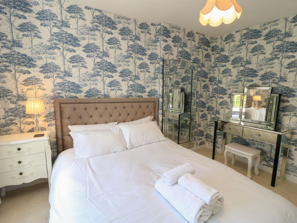 A bedroom with a bed, lamp, and dressing table at Waterloo Mill Cottage in Wotton-Under-Edge