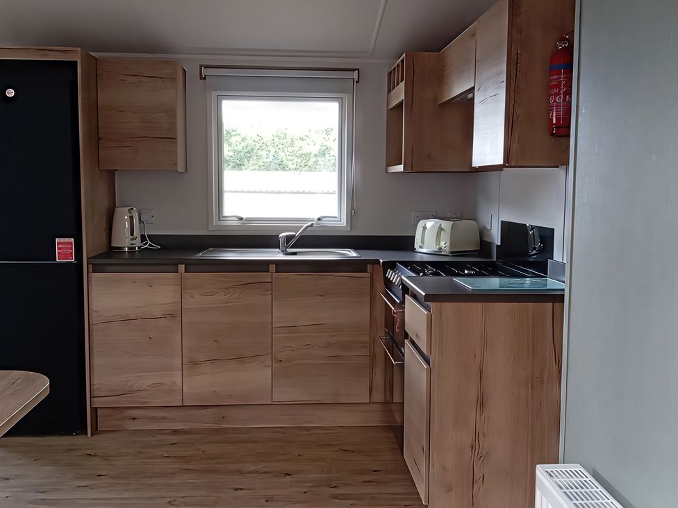 A kitchen with a sink, refrigerator, and stove at Caravan Thorness Bay Holiday Park Thorness Lane