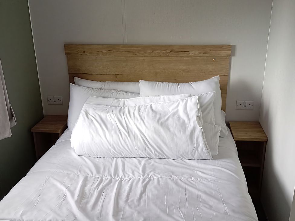 A bed with pillows and a bedside table at Caravan Thorness Bay Holiday Park Thorness Lane