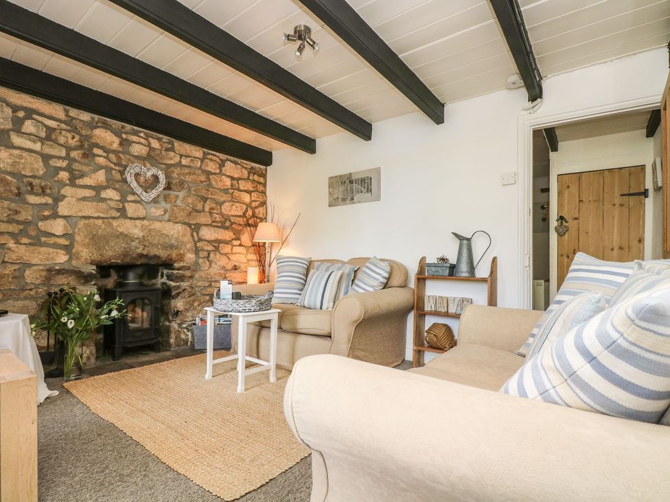 A living room with a stone wall and furniture at Driftwood Cottage in Helston