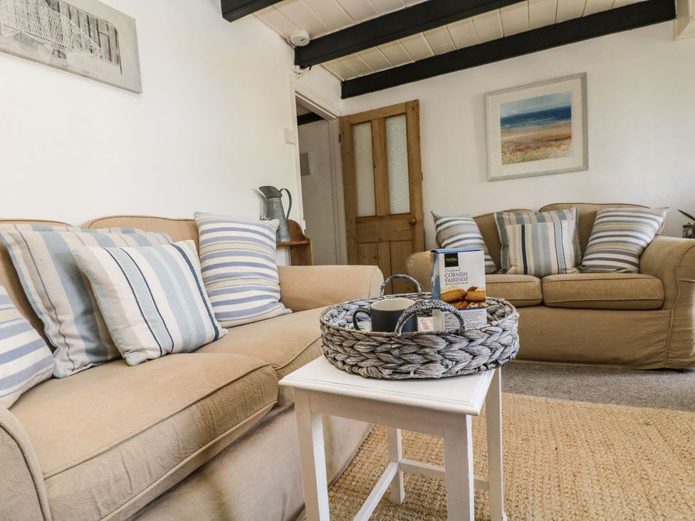 A living room with a sofa, table, and decorative items at Driftwood Cottage in Helston
