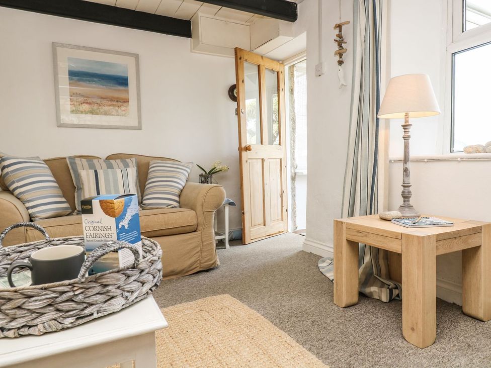 A living room with a sofa, coffee table, and lamp at Driftwood Cottage in Helston