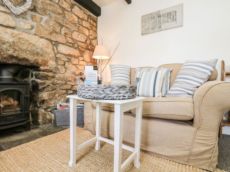 A living room with a sofa and stone wall at Driftwood Cottage in Helston