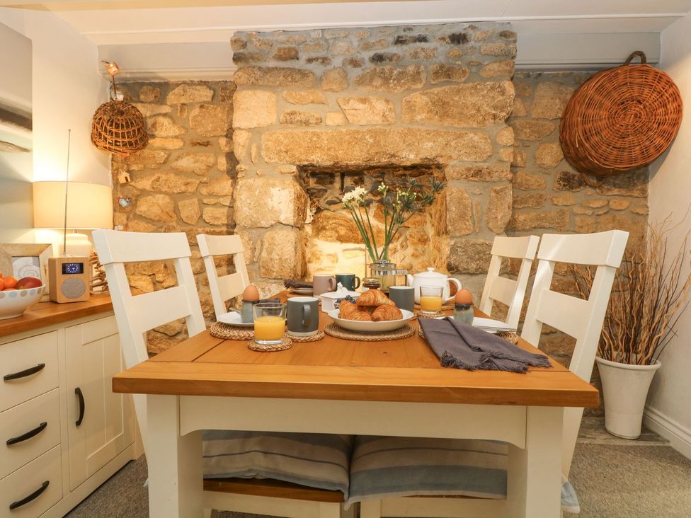 A dining room with a stone wall and table set for breakfast at Driftwood Cottage Helston