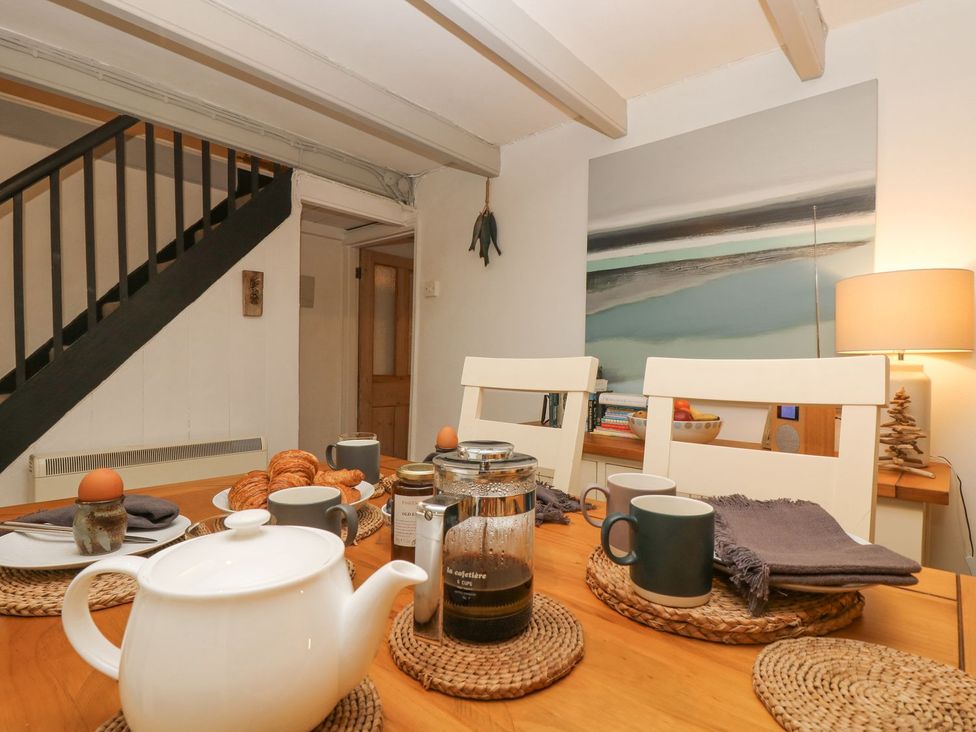 A dining room with a table set for tea at Driftwood Cottage in Helston