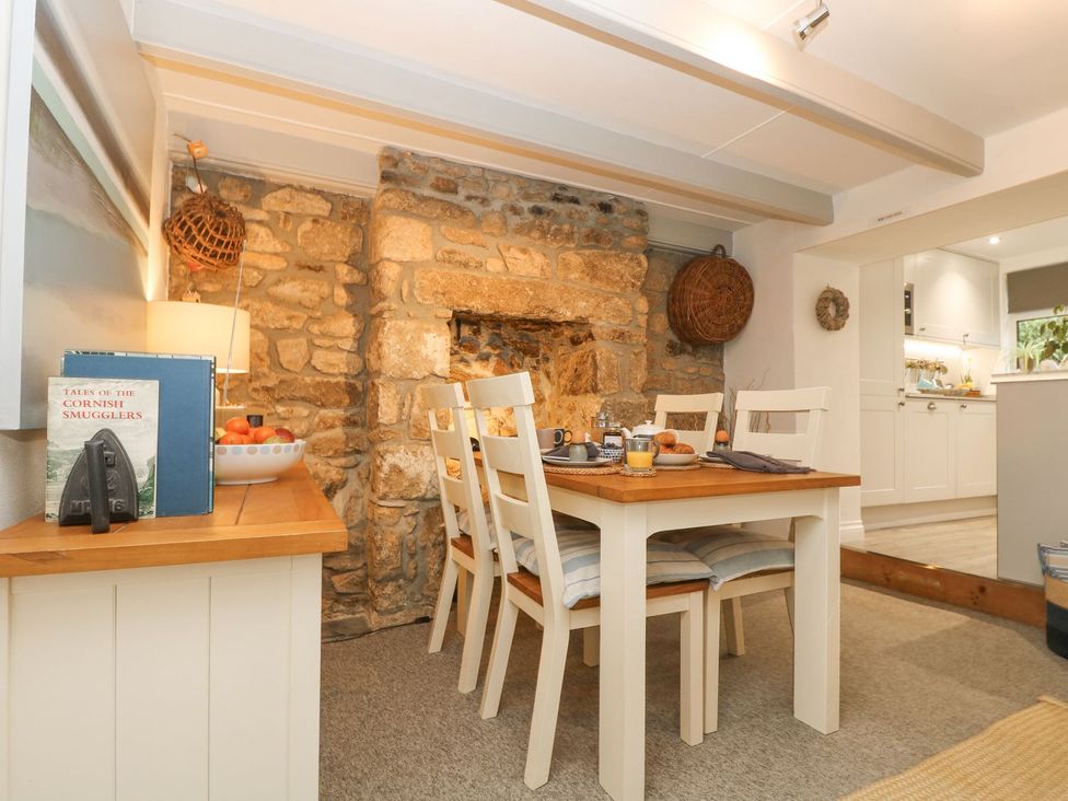 A dining room with a table set for meals at Driftwood Cottage in Helston