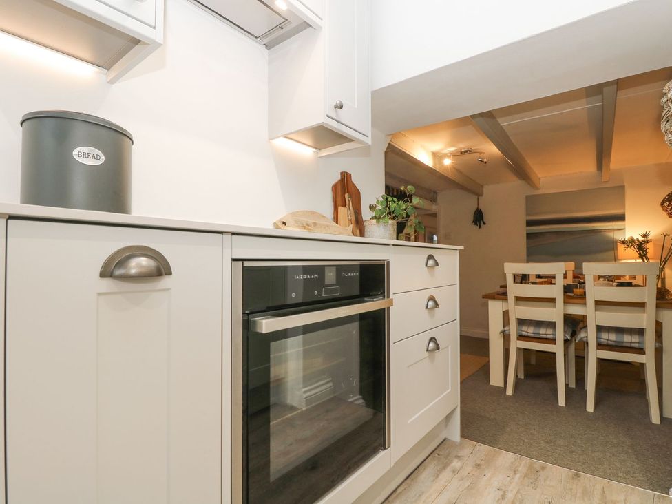 A kitchen with an oven and dining area at Driftwood Cottage in Helston