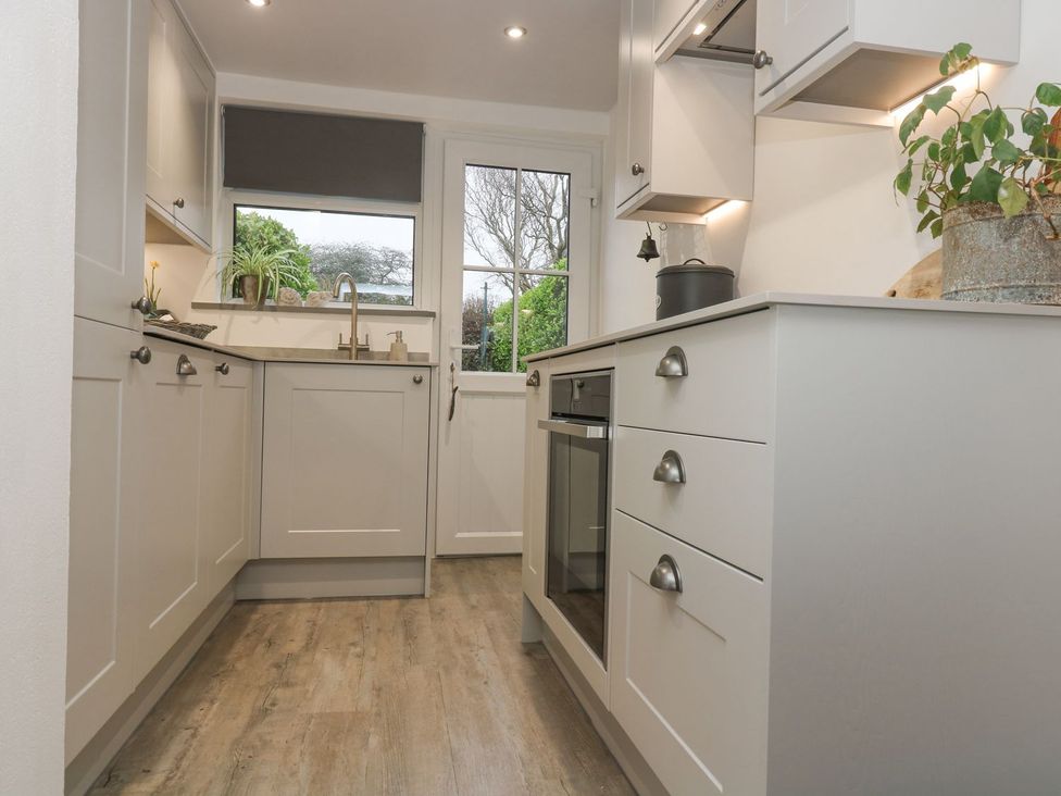 A kitchen with cabinets and a sink at Driftwood Cottage in Helston