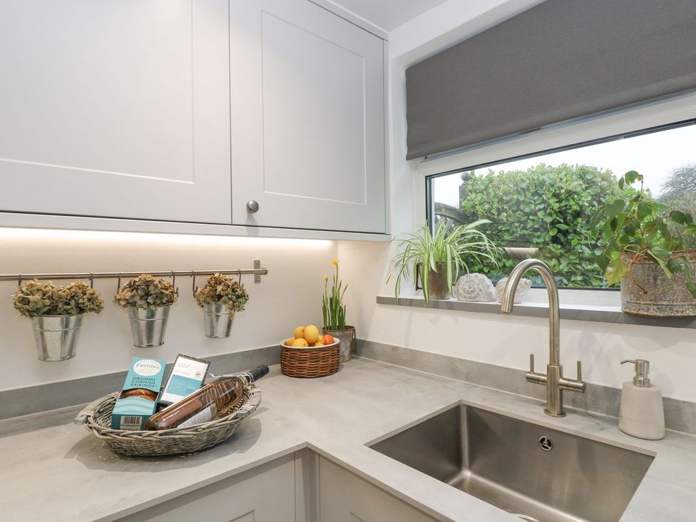 A kitchen with a sink and fruit basket at Driftwood Cottage in Helston