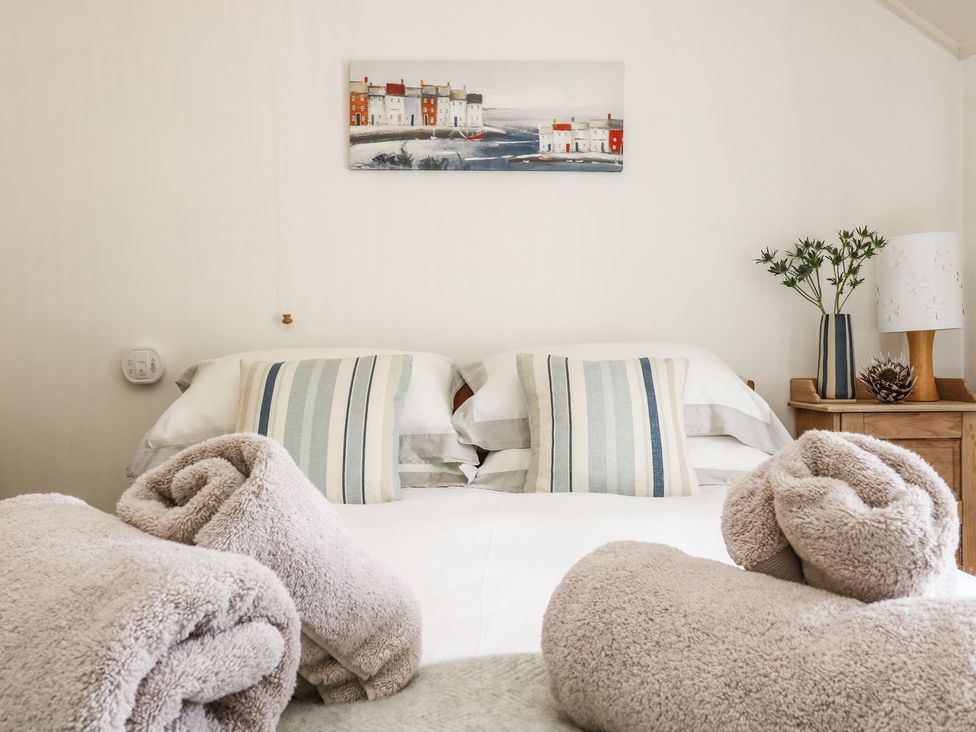 A bedroom with a bed and decorative items at Driftwood Cottage in Helston