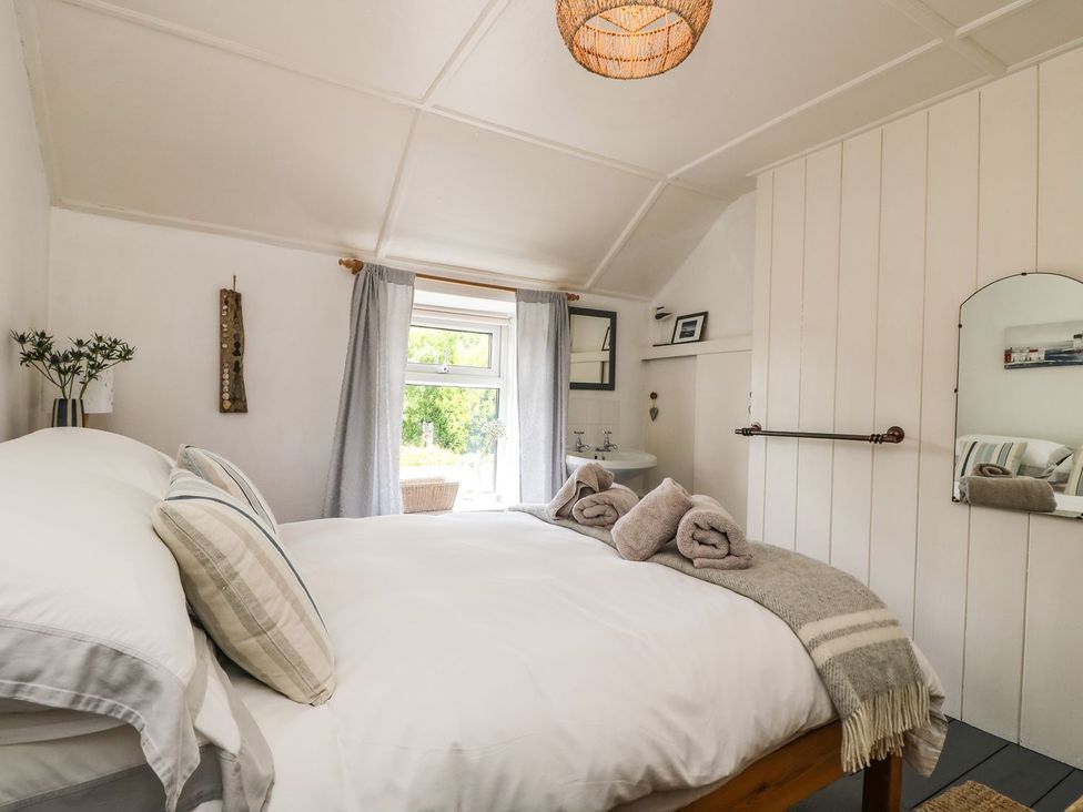 A bedroom with a bed and towels at Driftwood Cottage in Helston