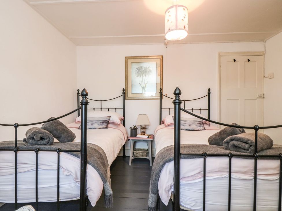 A bedroom with twin beds and a nightstand at Driftwood Cottage in Helston