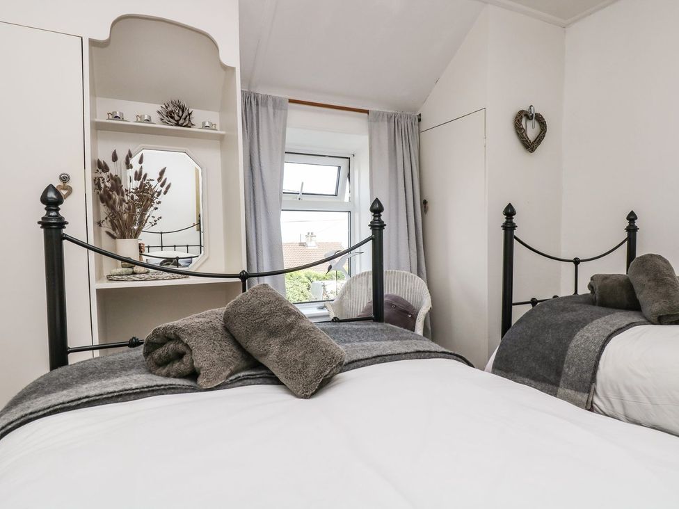 A bedroom with two beds and a window at Driftwood Cottage in Helston