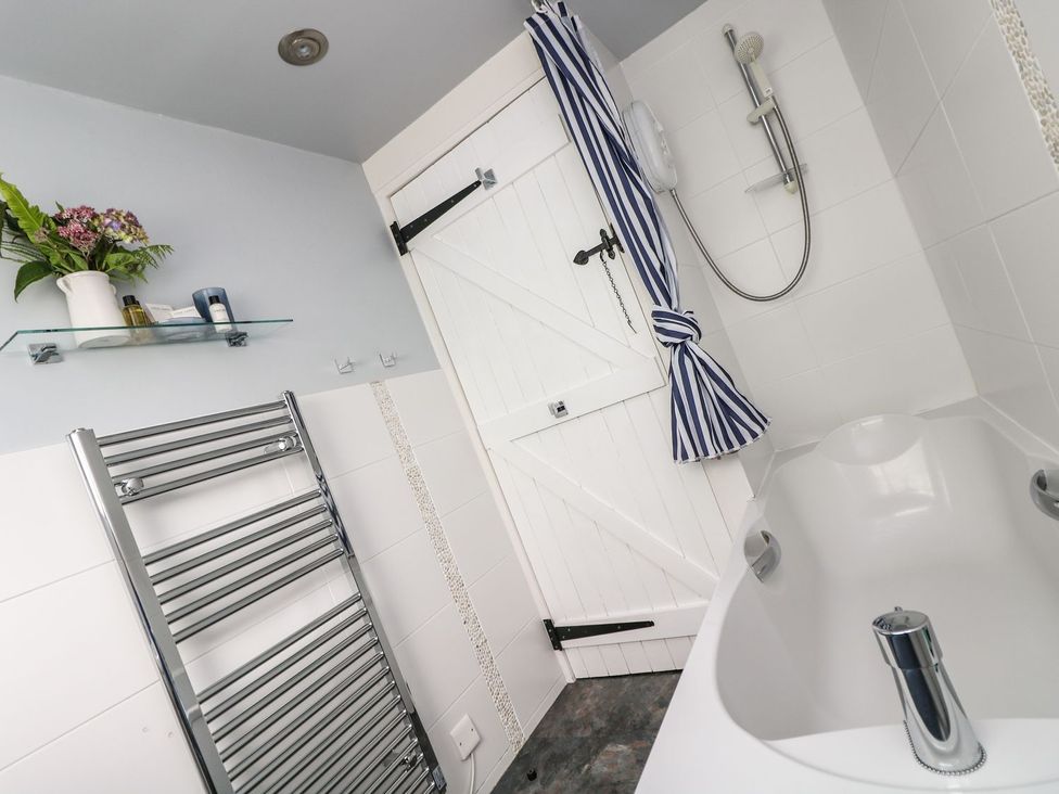 A bathroom with a bath tub and shower at Driftwood Cottage in Helston