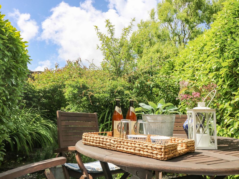 A garden table with drinks and plants at Driftwood Cottage Helston