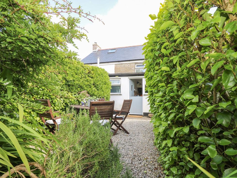 A garden with a table and chairs at Driftwood Cottage in Helston