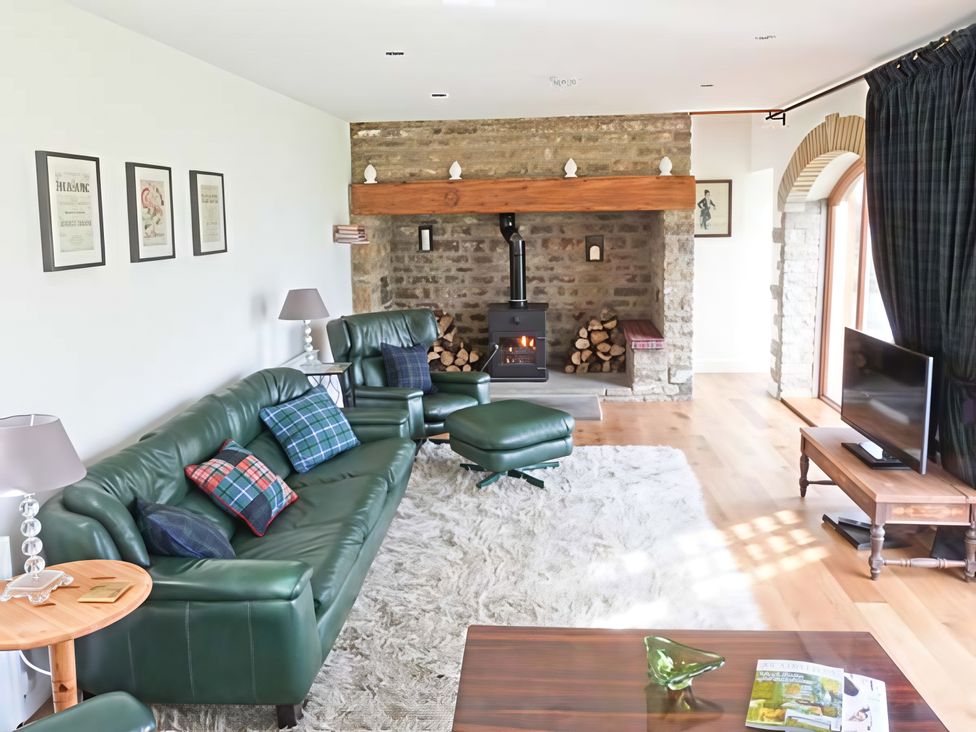 A living room with a fireplace and furniture at Beningborough