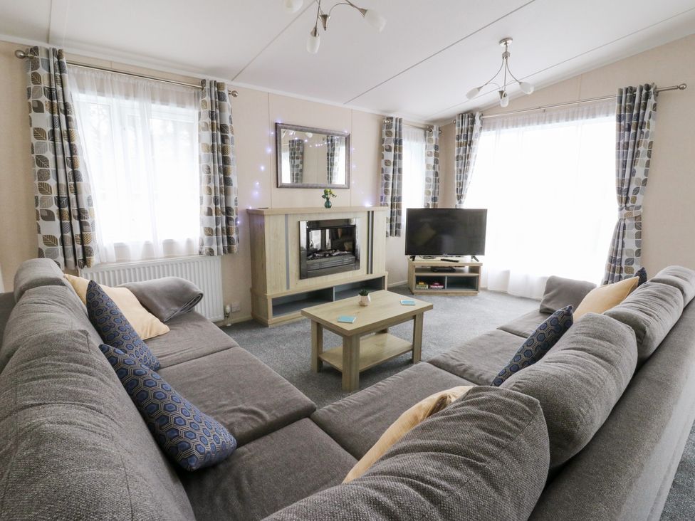 A living room with a sofa and television at Beechwood Lodge