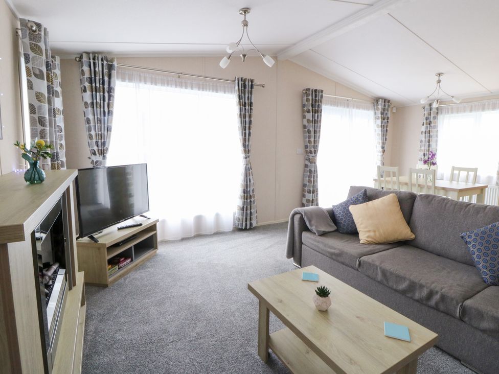 A living room with a sofa and a television at Beechwood Lodge