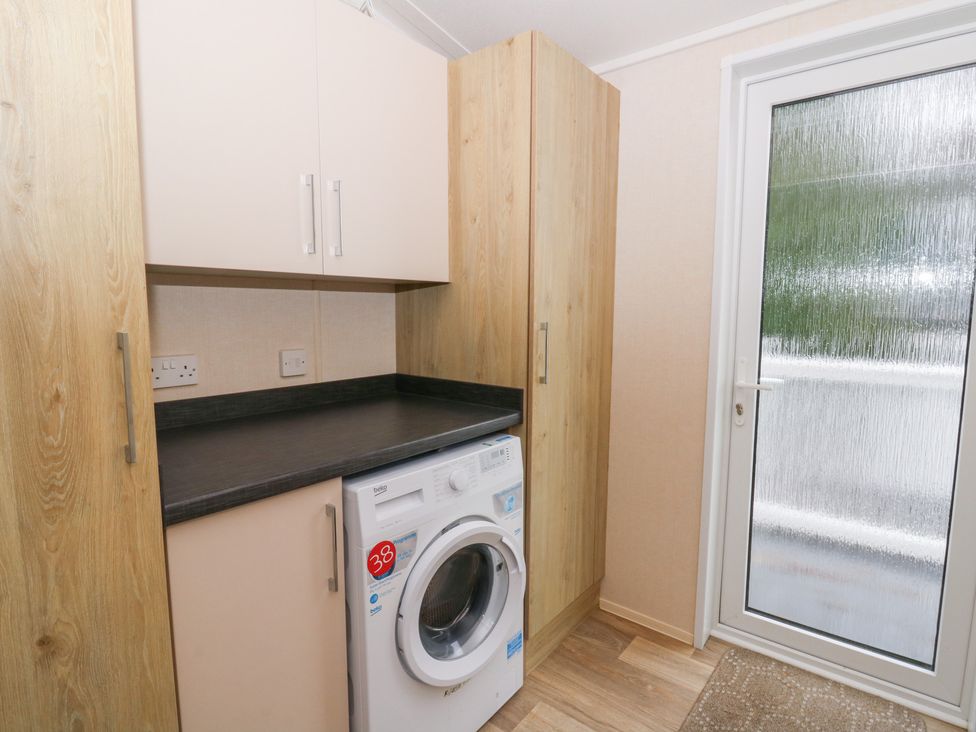 A laundry room with a washing machine and cabinets at Beechwood Lodge in 