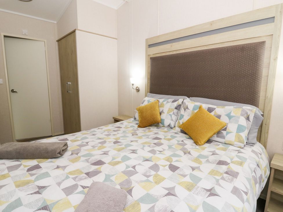 A bedroom with a large bed and wardrobe at Beechwood Lodge 