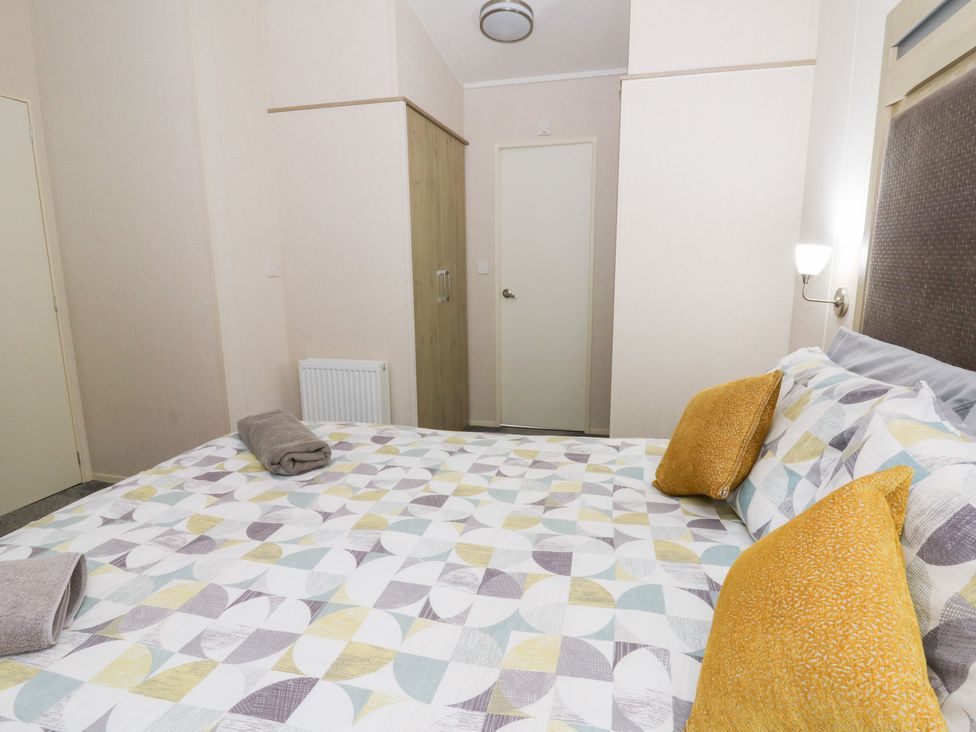 A bedroom with a bed, two pillows, and a wardrobe at Beechwood Lodge