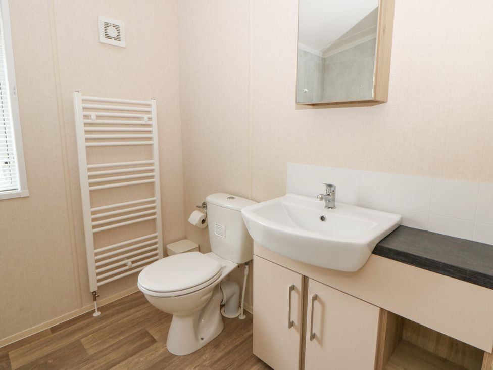 A bathroom with a sink, toilet, and towel radiator at Beechwood Lodge
