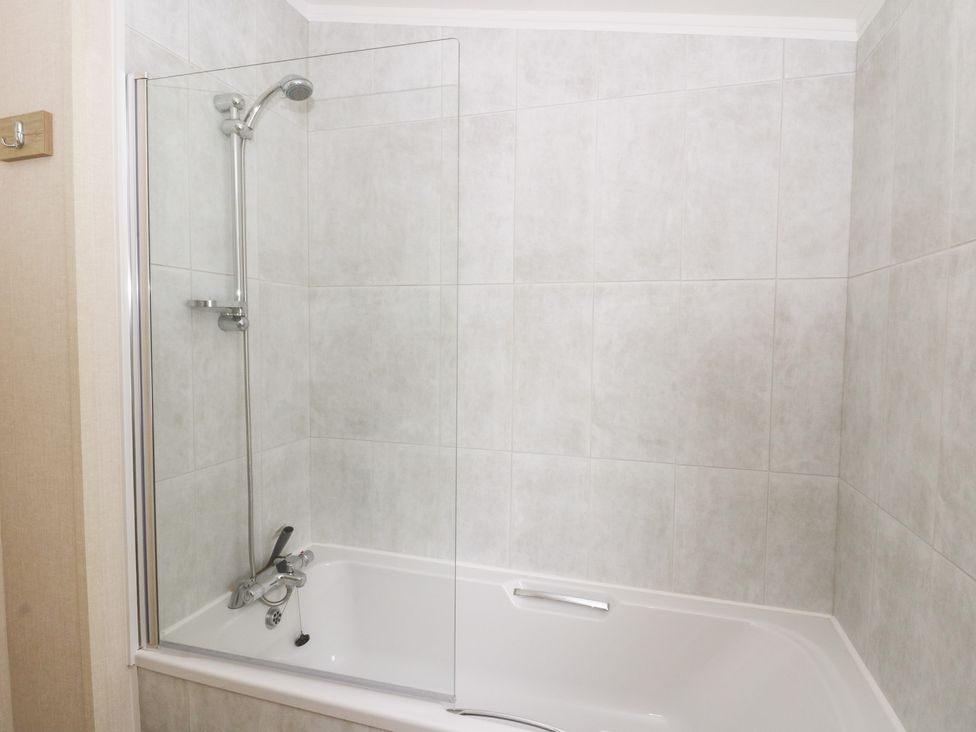 A bathtub with a glass shower partition and shower fixtures at Beechwood Lodge