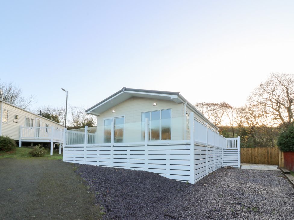 An exterior view of a lodge with a white fence at Beechwood Lodge