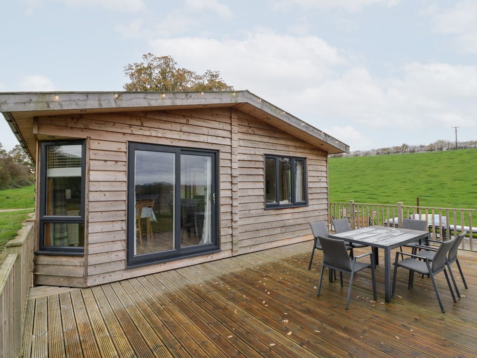 A wooden cabin with a deck and outdoor furniture at Elm Lodge Rugeley