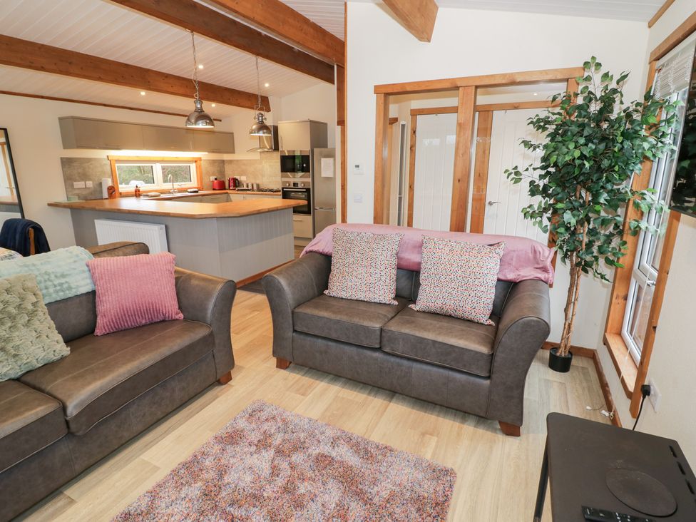 A living room with a sofa and kitchen area at Elm Lodge in Rugeley