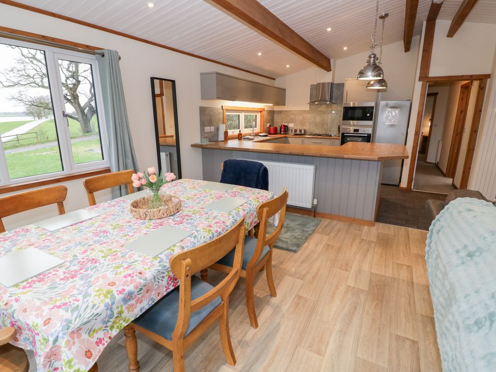 A dining room with a table and kitchen counter at Elm Lodge in Rugeley