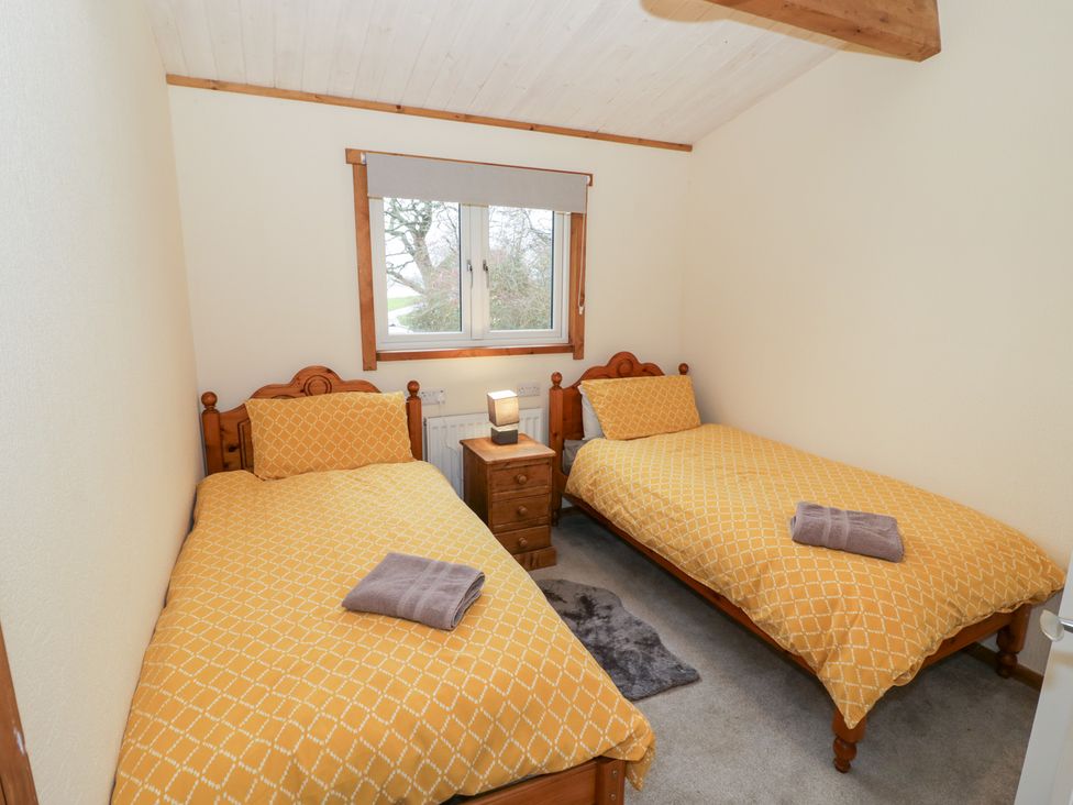 A bedroom with two single beds and a nightstand at Elm Lodge in Rugeley