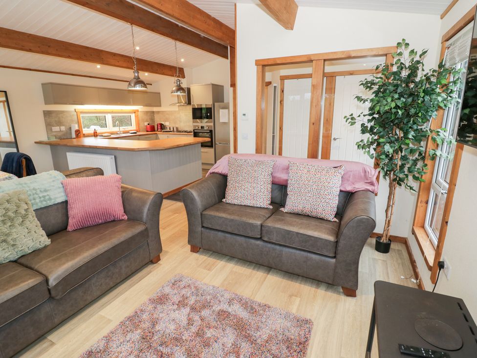 A living room with a sofa and kitchen area at Cedar Lodge in Rugeley