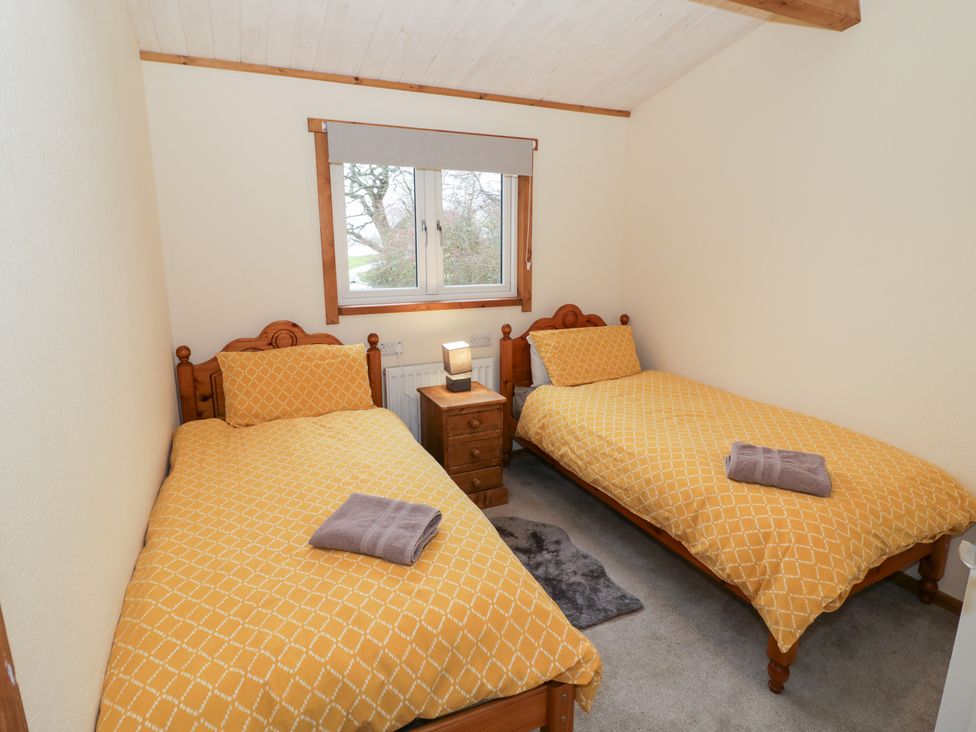 A bedroom with two single beds and a window at Cedar Lodge in Rugeley