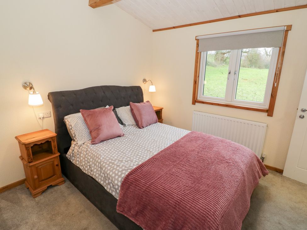A bedroom with a bed and bedside table at Cedar Lodge in Rugeley