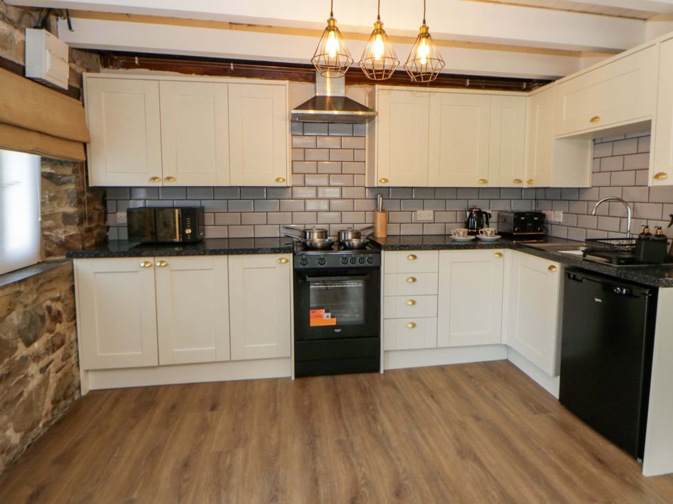 A kitchen with a stove, microwave, and sink at Shearers Llandysul