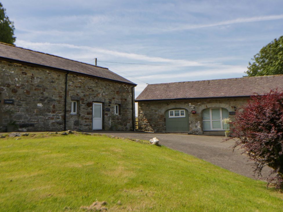 A stone building with a garage and landscaped garden at Shearers in Llandysul