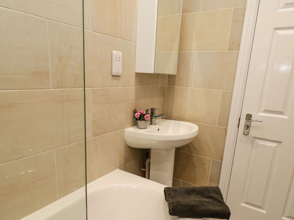 A bathroom with a sink, mirror, and bathtub at The Kesi Residence in Loftus