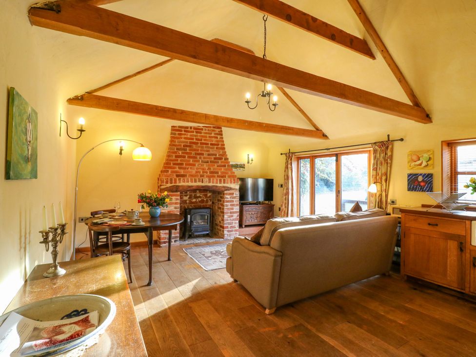 A living room with a fireplace and sofa at The Old Cow Shed in 