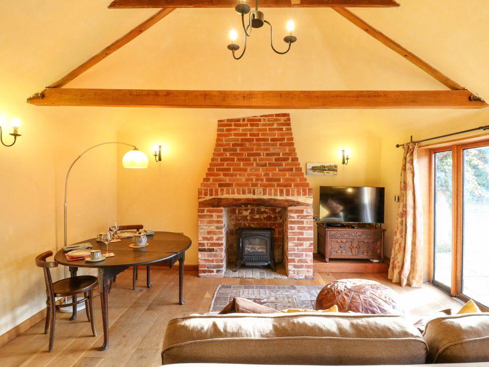 A living room with a fireplace and dining area at The Old Cow Shed