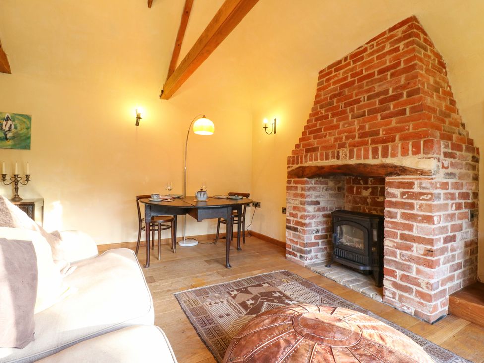 A living room with a fireplace and table at The Old Cow Shed in 