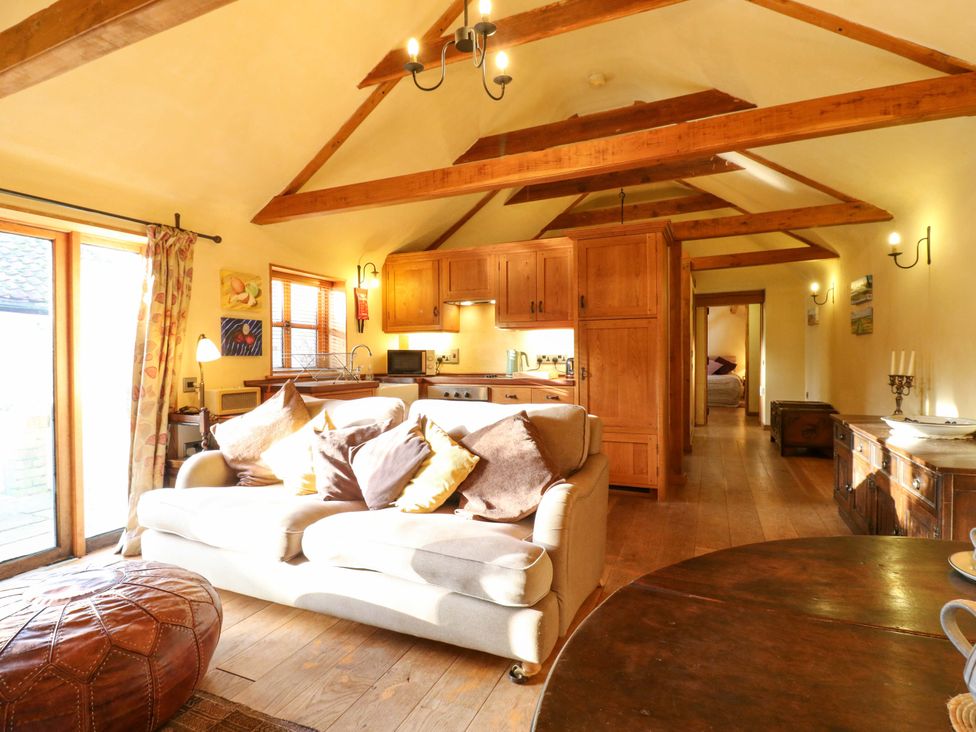 A living room with a sofa and wooden furniture at The Old Cow Shed in 