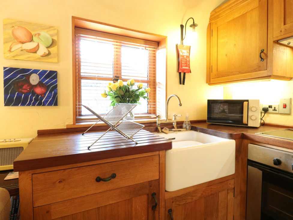 A kitchen with a sink and flowers on the counter at The Old Cow Shed 