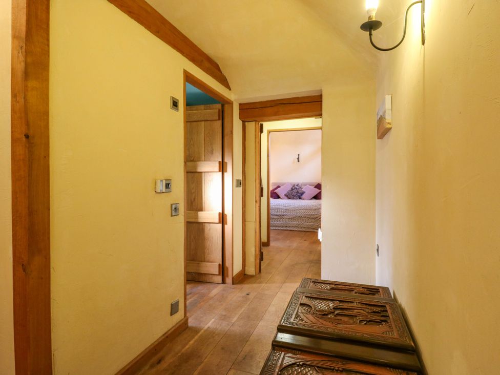A hallway with carved wooden benches and doors at The Old Cow Shed