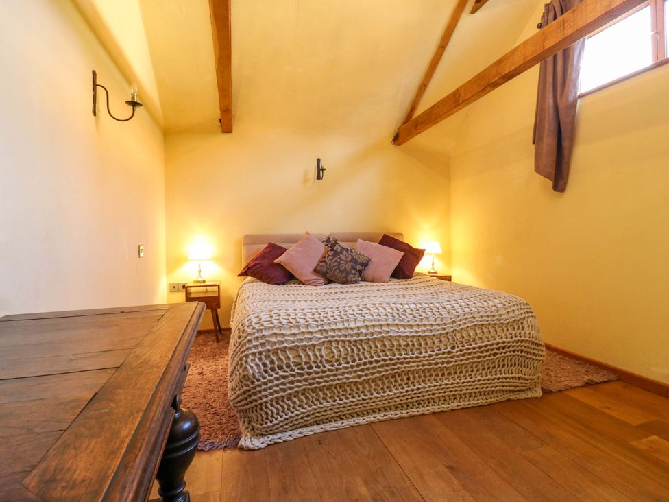 A bedroom with a bed and bedside table at The Old Cow Shed
