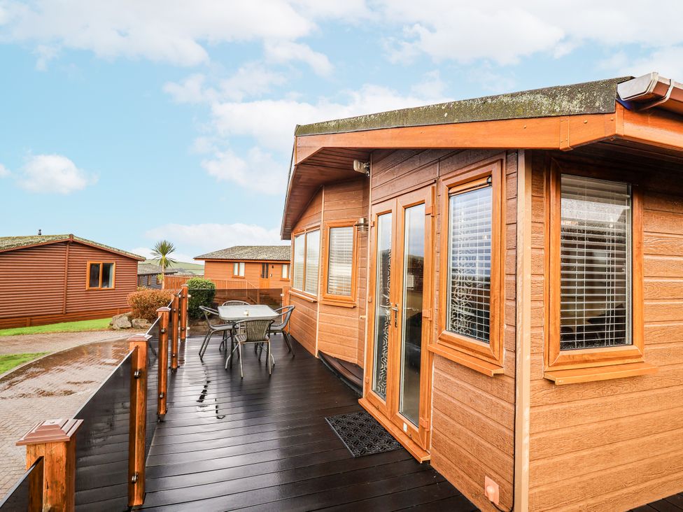 A wooden cabin with a deck and outdoor furniture at Ocean View in Ilfracombe