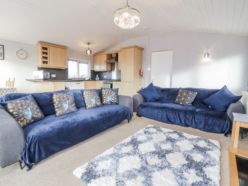 A living room with sofas and a kitchen area at Ocean View in Ilfracombe