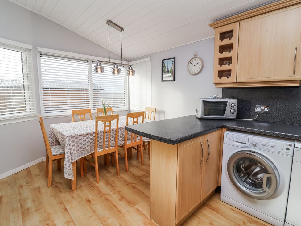 A kitchen with a dining table and washing machine at Ocean View in Ilfracombe